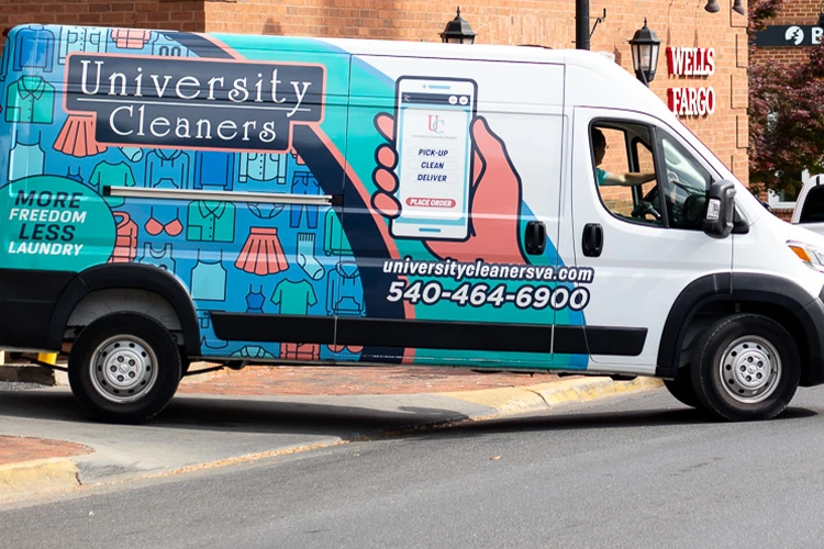 A University Cleaners van is parked on the street, displaying its logo, contact information, and an illustration promoting laundry pick-up and delivery service.