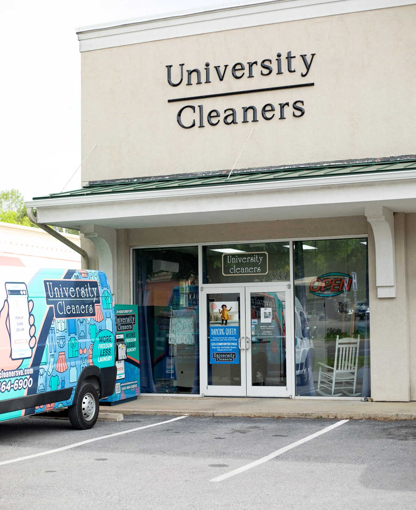 Storefront of University Cleaners with a branded van parked outside and an "OPEN" sign in the window.