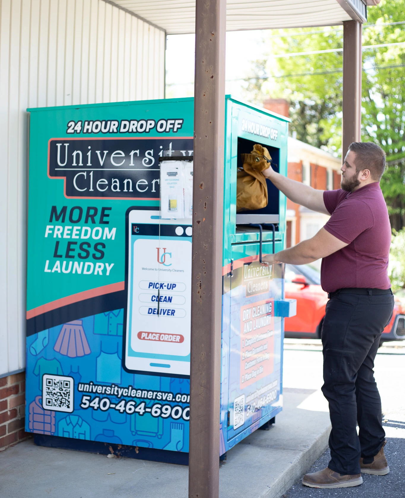 A man deposits a bag into a 24-hour drop-off kiosk at University Cleaners, which advertises pick-up and delivery laundry services.